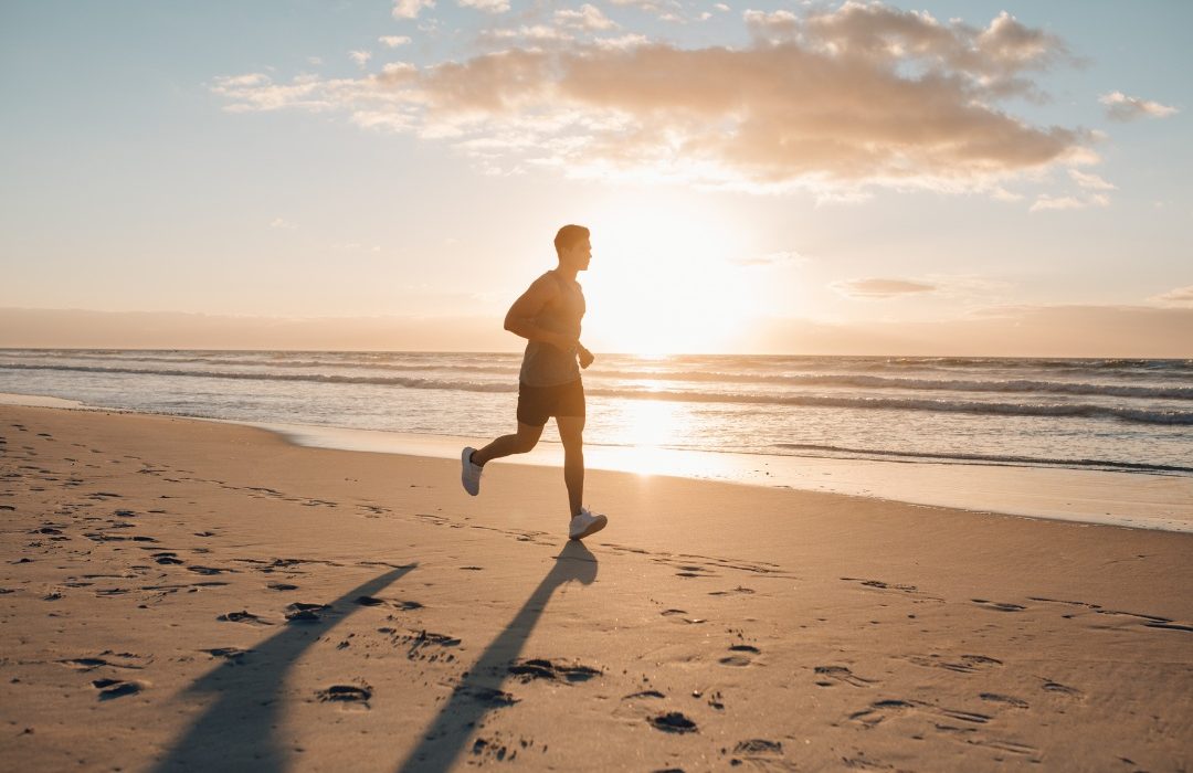 man running down the beach at sunrise