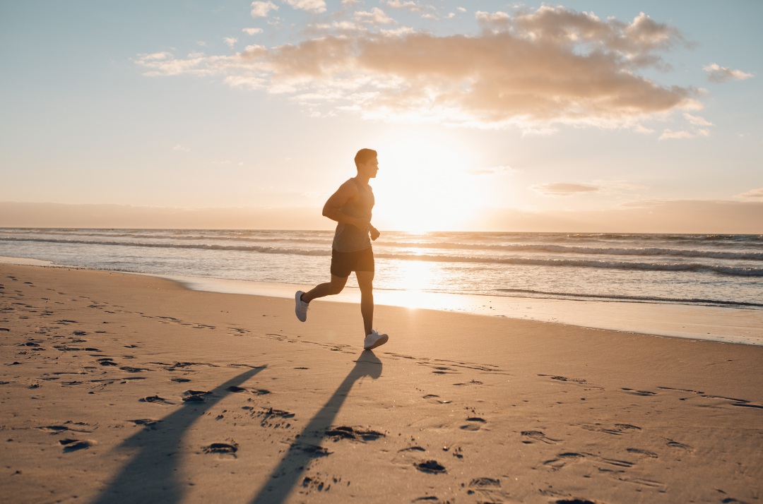 man running down the beach at sunrise