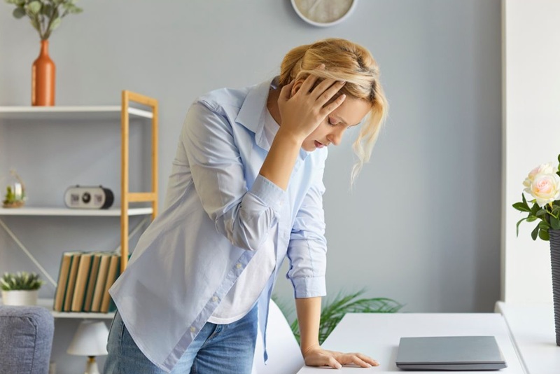 woman standing up holding her head from dizziness