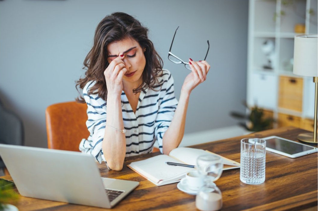 woman at work closing her eyes because of migraine